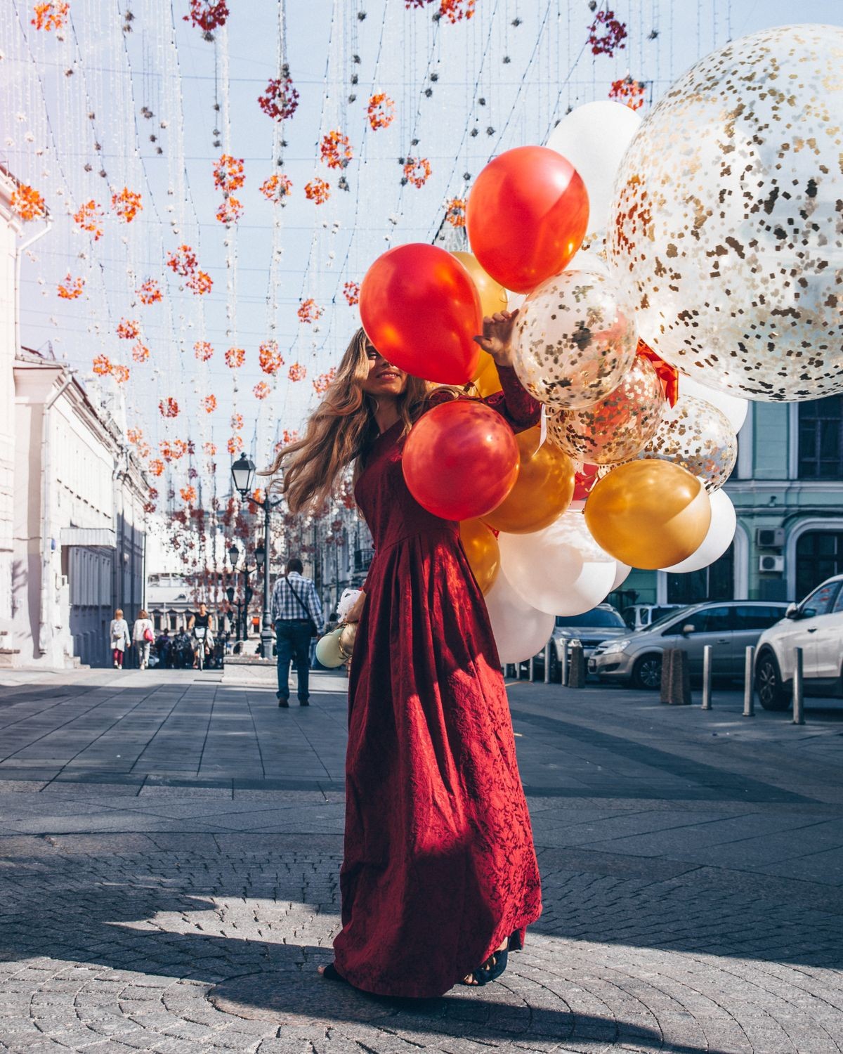 Beautiful woman in Red dress is so happy to walk with a lot of balloons